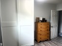 White two-panel sliding closet doors with light gray walls and wood-finish flooring - 4812 47 St, Drayton Valley, AB 