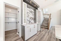 Wet bar with integrated sink, floating shelves, and marble-patterned backsplash - 