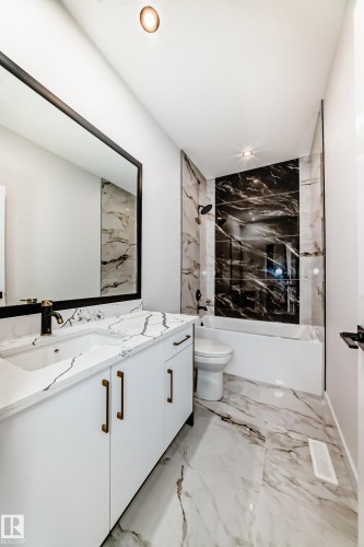 Bathroom featuring a white vanity with undermount sink, a large framed mirror, and a coordinated countertop - 14 Tenuto Link, Spruce Grove, AB - Indoor Photo Showing Bathroom