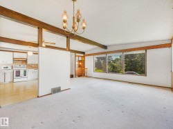 Spacious interior featuring a brass chandelier, exposed wood beams, and a large window array - 