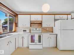 Kitchen featuring white cabinetry, a dual basin stainless steel sink, and a mosaic tile backsplash - 