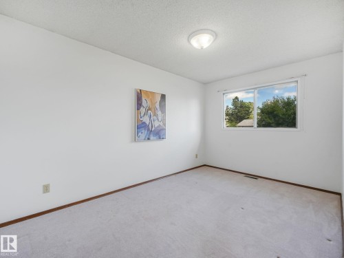 Bright room with a large window, neutral carpeting, and white walls - 15011 72A Street, Edmonton, AB 