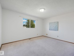 Spacious interior room featuring a large window, neutral wall paint, and overhead lighting - 