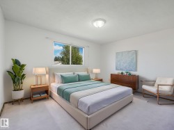 Light-filled bedroom featuring a large window, neutral wall paint, and white textured carpeting - 