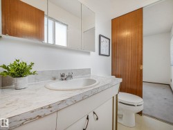 Bathroom featuring a built-in vanity with a white countertop and integrated sink, chrome faucet, and white cabinetry - 