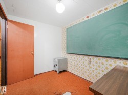 Interior room featuring a large green chalkboard, patterned wallpaper, orange carpeting, a solid core door, and an overhead light fixture - 