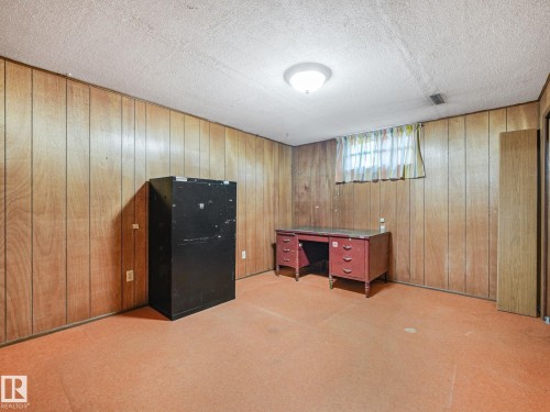 Room featuring wood paneling on walls, carpeted flooring, and a flush-mount ceiling light fixture - 15011 72A Street, Edmonton, AB 