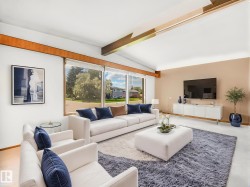 Vaulted ceiling with exposed wood beams, expansive windows, wood-finish flooring, and a neutral color palette create a bright, open living space - 