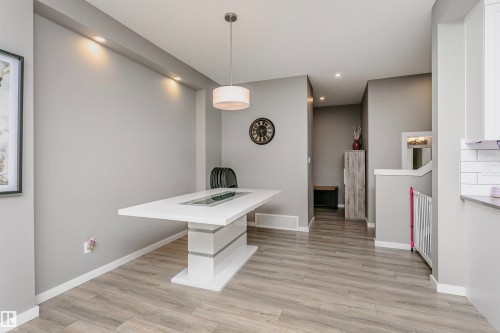 Dining area featuring a modern white pedestal table with a recessed centerpiece - 7322 Chivers Crescent, Edmonton, AB 