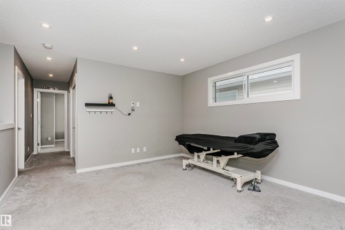 Spacious room featuring light gray walls, light gray carpet, recessed lighting, and a horizontal window - 7322 Chivers Crescent, Edmonton, AB 