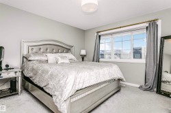 Bedroom featuring light gray wall paint, light-colored carpet flooring, a large window with white trim, and a semi-flush mount ceiling light fixture - 