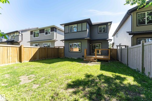 Spacious backyard featuring a wooden deck with railing, sliding glass door access, and a manicured lawn - 7322 Chivers Crescent, Edmonton, AB 