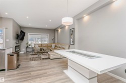 Open-concept living space featuring wood-finish flooring, recessed lighting, and a white kitchen island with integrated lighting - 