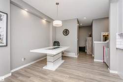 Spacious dining area featuring wood-finish flooring, recessed ceiling lighting, a modern white chandelier, and a built-in kitchen peninsula - 