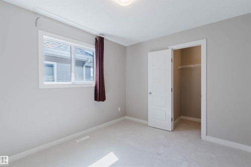 Neutral tone wall paint with white trim, a large window, and a built-in closet with shelving and hanging rod - 2472 Glenridding Boulevard, Edmonton, AB 
