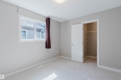Neutral tone wall paint with white trim, a large window, and a built-in closet with shelving and hanging rod - 