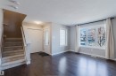 Entryway featuring dark wood-finish flooring, a carpeted staircase, and a white paneled front door with decorative glass - 2472 Glenridding Boulevard, Edmonton, AB 