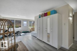 Sunlit room featuring wood-finish flooring, a full wall of windows, and a white paneled door - 