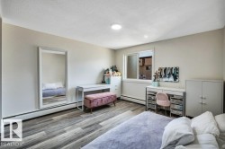 Spacious room featuring wood-finish flooring, a large window, baseboard heating, and light-colored walls - 