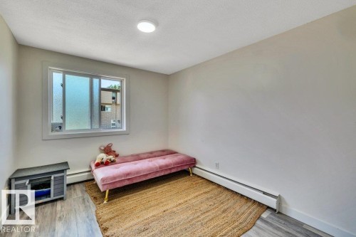 Room featuring wood-finish flooring, a baseboard heating unit, and a frosted glass window - 102 7805 159 Street, Edmonton, AB 