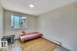 Room featuring wood-finish flooring, a baseboard heating unit, and a frosted glass window - 