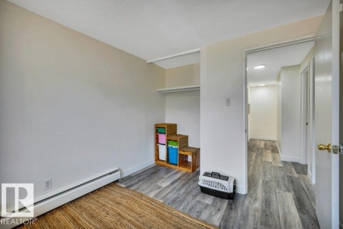 Interior room featuring wood-finish flooring, light neutral wall paint, and a built-in closet space - 102 7805 159 Street, Edmonton, AB 