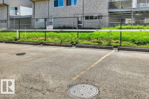 Paved parking area with a striped parking space and a manhole cover - 102 7805 159 Street, Edmonton, AB 