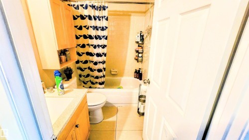Bathroom with shower / bath combination with curtain, vanity, and light tile patterned floors - 704 Abbottsfield Road, Edmonton, AB - Indoor Photo Showing Bathroom