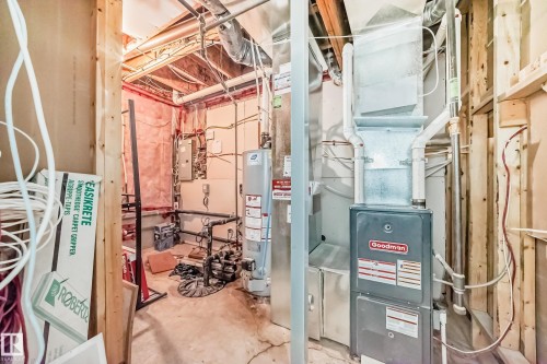 Mechanical room featuring a Goodman furnace, water heater, exposed ductwork, and electrical panel - 2 12042 101 Street, Edmonton, AB 