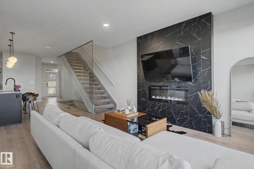 Living area featuring a modern fireplace with black marble-look tile surround and an integrated electric fireplace - 3313 Kulay Way, Edmonton, AB 