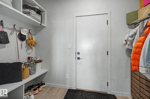 Entryway featuring light-toned wood-finish flooring, a contemporary white door with dark hardware, and light gray walls - 3313 Kulay Way, Edmonton, AB 