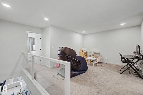Spacious carpeted bonus room featuring recessed lighting and a contemporary glass panel railing - 3313 Kulay Way, Edmonton, AB 