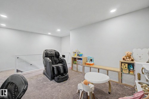Carpeted loft area featuring recessed lighting, a clear panel railing system, and light wood-finish built-in shelving with integrated bench seating - 3313 Kulay Way, Edmonton, AB 