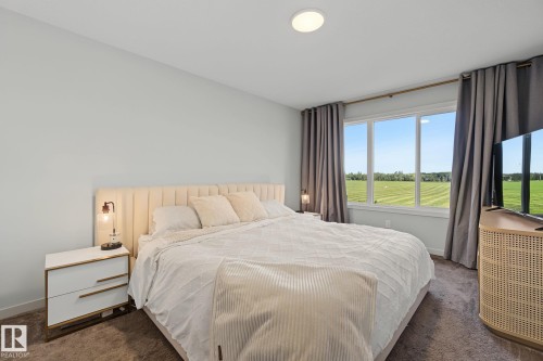 Bedroom featuring a light-colored accent wall, expansive window with outdoor scenery, recessed ceiling light, and wall-to-wall carpeting - 3313 Kulay Way, Edmonton, AB 