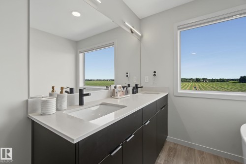 Modern bathroom featuring a double vanity with stone countertops, integrated sinks, and matte black faucets - 3313 Kulay Way, Edmonton, AB 