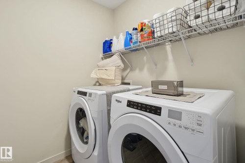 Dedicated laundry area featuring a front-loading washer and dryer, neutral wall paint, and overhead wire shelving for storage - 3313 Kulay Way, Edmonton, AB 