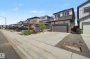 Modern two-story residence featuring a dark gray garage door, stone accents, and a contrasting light facade - 3313 Kulay Way, Edmonton, AB 