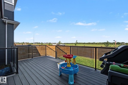 Spacious deck featuring composite decking, black aluminum railings with glass panels, and a privacy fence - 3313 Kulay Way, Edmonton, AB 