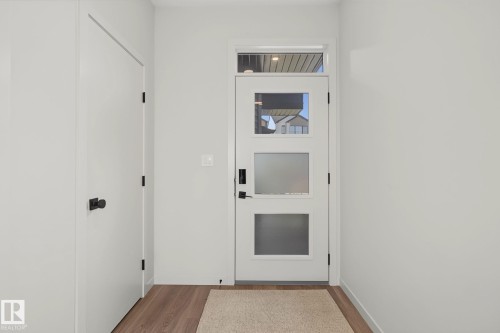 Contemporary entry door with frosted panels, a clear upper panel, and an overhead transom window - 3313 Kulay Way, Edmonton, AB 