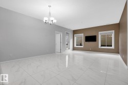 Spacious room featuring large format tile flooring, a contemporary chandelier, multiple windows, and a neutral color palette - 