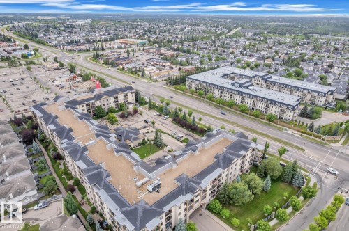 Expansive residential development featuring multiple low-rise buildings with light-colored facades and dark-pitched roofs - 105 160 Magrath Road, Edmonton, AB 