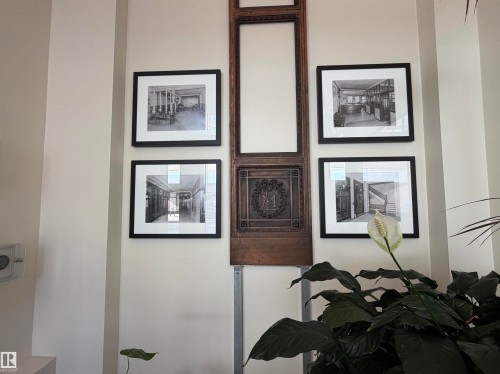 Wall art installation featuring four framed monochrome prints, a decorative wood panel, and an ornate metal emblem - #210 10134 100 St Nw, Edmonton, AB - Indoor Photo Showing Other Room