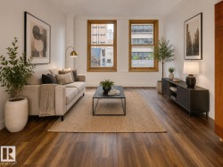 Spacious living area featuring wood-finish flooring, high ceilings, and significant natural light through multiple large windows with wood trim - 