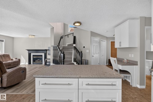 Kitchen island featuring a stone-finish countertop and white cabinetry with brushed nickel hardware - 2327 37B Avenue, Edmonton, AB 