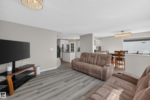 Living area with wood-finish flooring, a contemporary chandelier, and light gray wall paint - 2327 37B Avenue, Edmonton, AB 