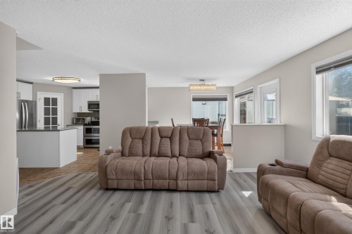 Spacious open-concept living area featuring wood-finish flooring and neutral wall tones - 2327 37B Avenue, Edmonton, AB 