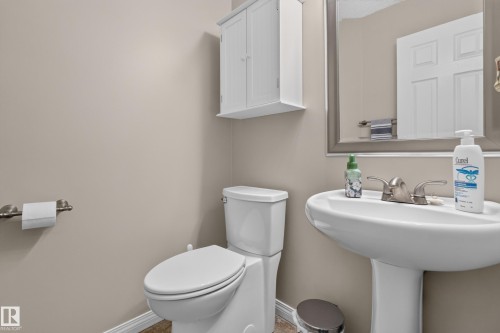 Pedestal sink with brushed nickel faucet, framed mirror, and white wall-mounted cabinet - 2327 37B Avenue, Edmonton, AB 