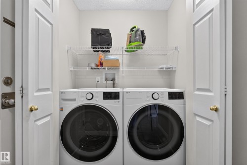Dedicated laundry closet featuring a full-size washer and dryer, white wire shelving, and bi-fold doors - 2327 37B Avenue, Edmonton, AB 