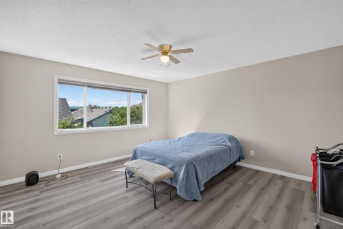 Spacious room featuring wood-finish flooring, a large window, and a ceiling fan with integrated lighting - 2327 37B Avenue, Edmonton, AB 