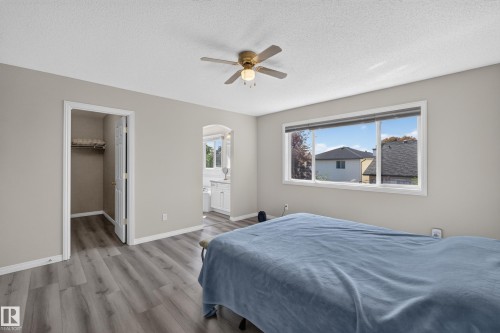 Bedroom featuring wood-finish flooring, a ceiling fan, and a large window overlooking neighboring rooftops - 2327 37B Avenue, Edmonton, AB 